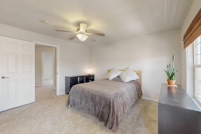 bedroom featuring baseboards, light colored carpet, and a ceiling fan