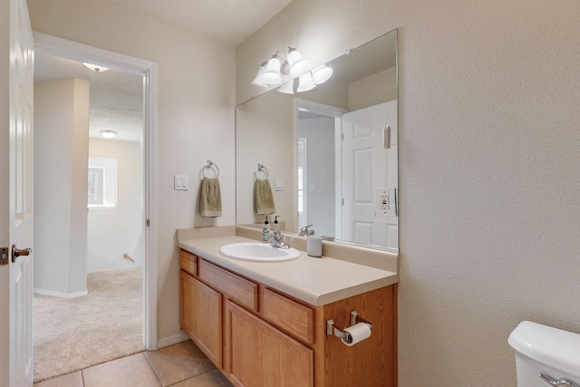 half bathroom with baseboards, toilet, vanity, and tile patterned flooring