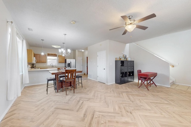 dining room featuring visible vents, ceiling fan with notable chandelier, baseboards, and a textured ceiling