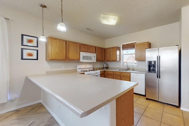 kitchen featuring white appliances, light countertops, a peninsula, and a sink