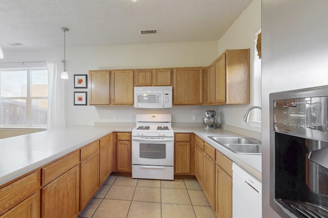 kitchen featuring visible vents, a sink, white appliances, light tile patterned flooring, and light countertops