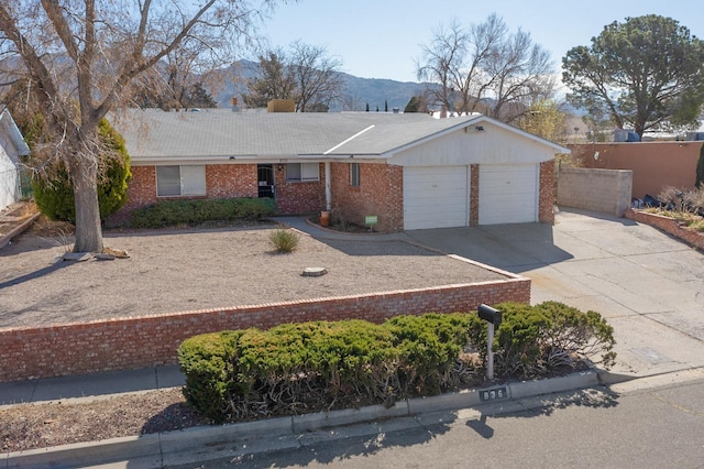 single story home with brick siding, a mountain view, concrete driveway, and a garage