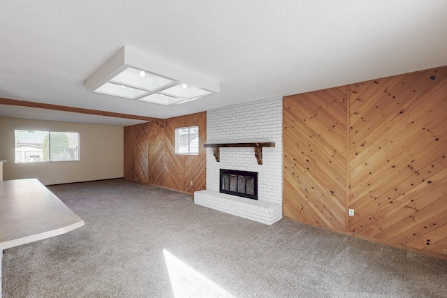 unfurnished living room with wooden walls, a brick fireplace, and carpet floors