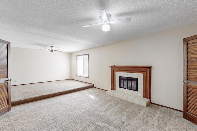 unfurnished living room featuring carpet flooring, a ceiling fan, and a tile fireplace