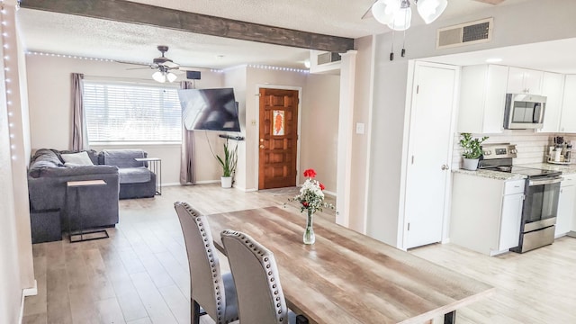 dining space featuring light wood-type flooring, visible vents, a textured ceiling, and a ceiling fan