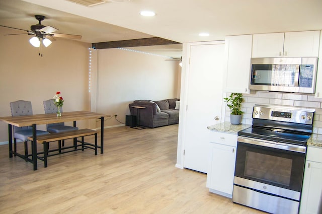 kitchen with tasteful backsplash, light stone countertops, light wood-type flooring, appliances with stainless steel finishes, and white cabinetry