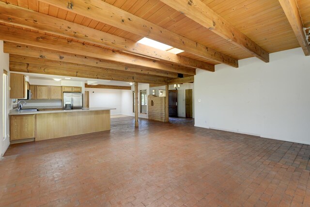 unfurnished living room featuring beamed ceiling, wooden ceiling, brick floor, and a sink