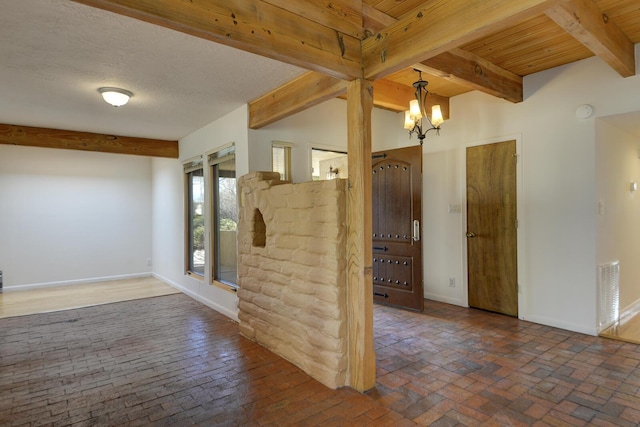 interior space featuring visible vents, baseboards, beam ceiling, brick floor, and a notable chandelier