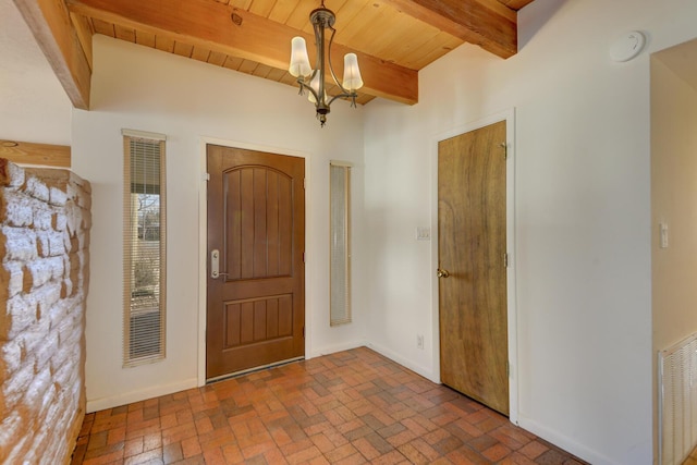 foyer entrance featuring visible vents, a chandelier, beamed ceiling, wood ceiling, and brick floor