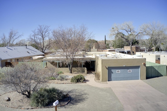 view of front of home featuring an attached garage, a chimney, driveway, and stucco siding