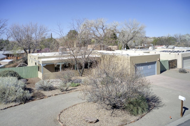 exterior space with stucco siding, driveway, a garage, and fence