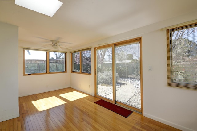 unfurnished sunroom featuring ceiling fan and a skylight