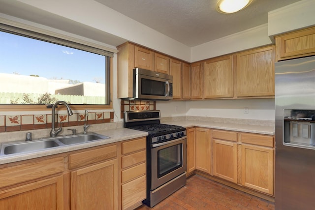 kitchen with a sink, light countertops, brick floor, and stainless steel appliances