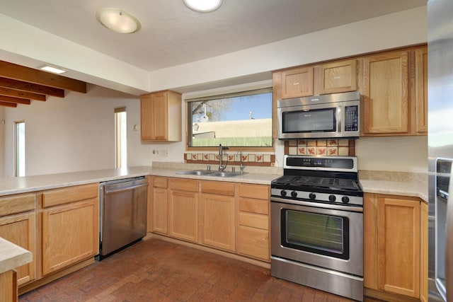 kitchen with a sink, stainless steel appliances, brick floor, and light countertops