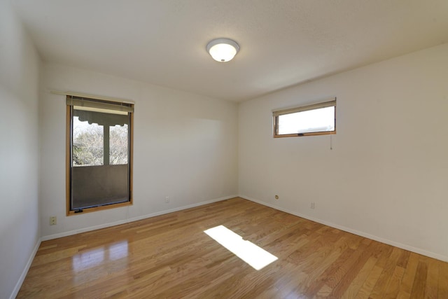 spare room featuring baseboards and light wood finished floors