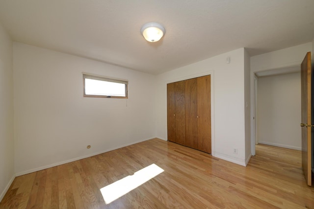 unfurnished bedroom featuring a closet, baseboards, and light wood-style flooring