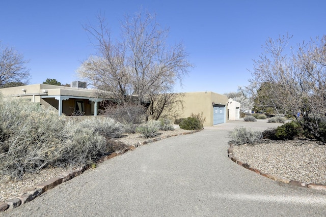 adobe home with a garage, driveway, and stucco siding