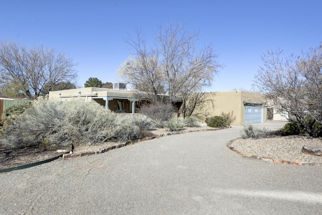 pueblo-style home with concrete driveway, an attached garage, and stucco siding