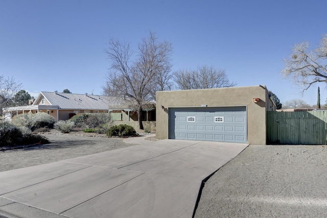 view of front of home featuring stucco siding, driveway, a garage, and fence