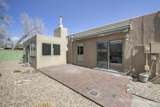 back of house with a patio area, stucco siding, a chimney, and fence