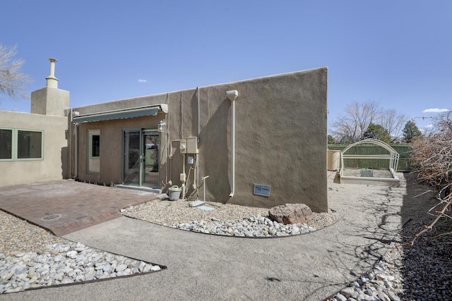 rear view of property with stucco siding and a patio