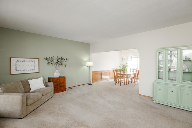 carpeted living room with baseboards and a chandelier