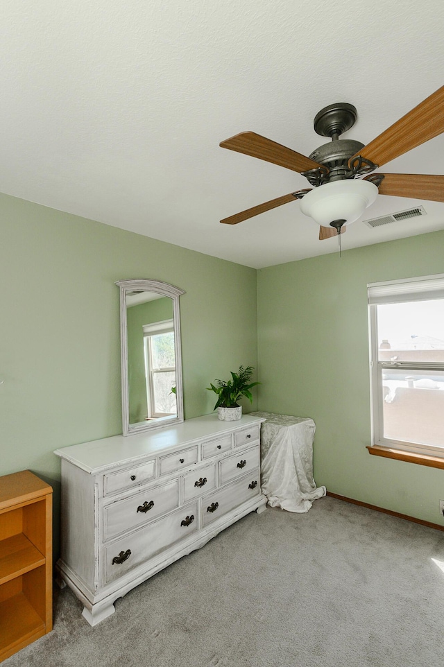 unfurnished bedroom with carpet flooring, multiple windows, a ceiling fan, and visible vents