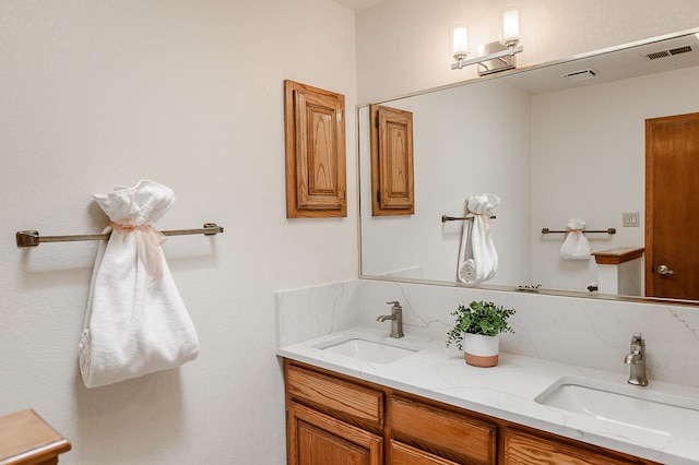 bathroom with double vanity, visible vents, and a sink