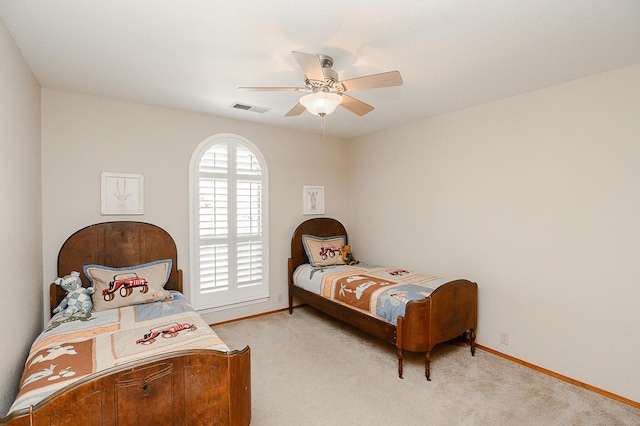 bedroom featuring visible vents, light colored carpet, baseboards, and ceiling fan