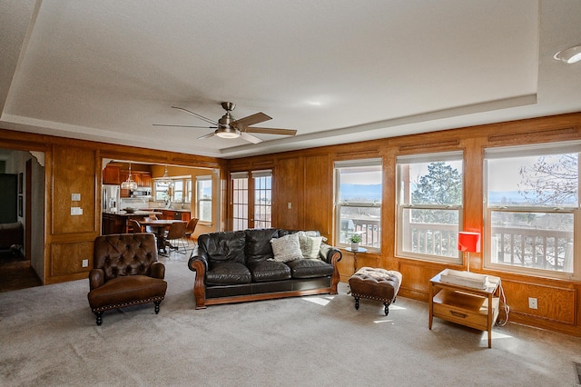 living room featuring plenty of natural light, carpet, ceiling fan, and wooden walls