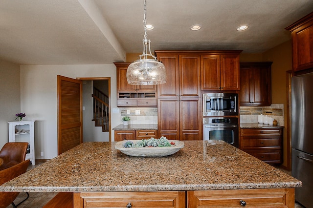 kitchen featuring decorative backsplash, light stone countertops, a kitchen island, and appliances with stainless steel finishes