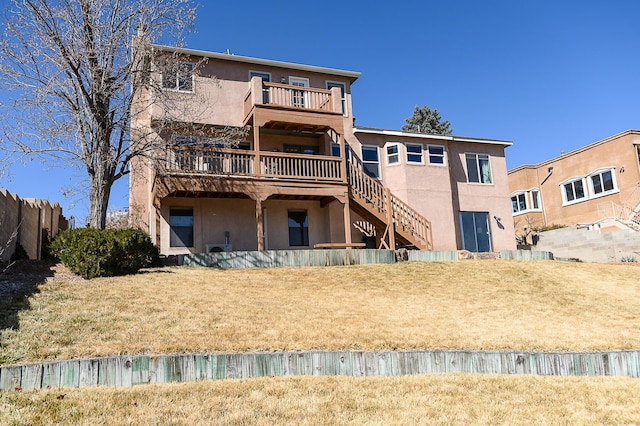 back of house featuring stairway, a yard, a deck, and stucco siding