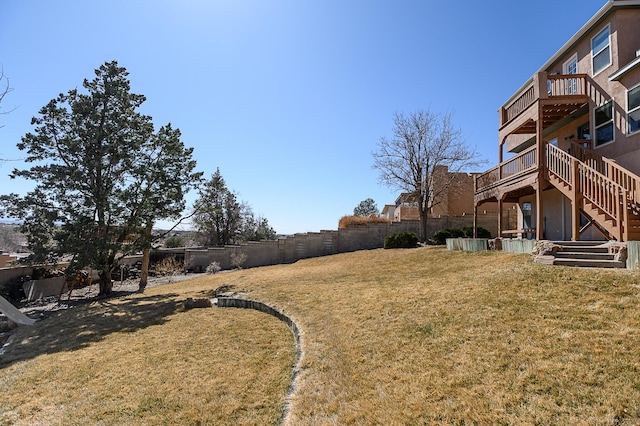 view of yard featuring a wooden deck, stairs, and fence