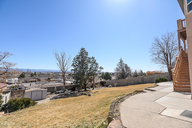 view of yard with an outbuilding, a fenced backyard, a shed, and a patio area