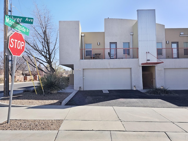 view of front of home featuring a balcony, an attached garage, driveway, and stucco siding