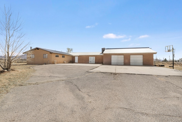 view of front of property with a garage, metal roof, concrete driveway, and stucco siding