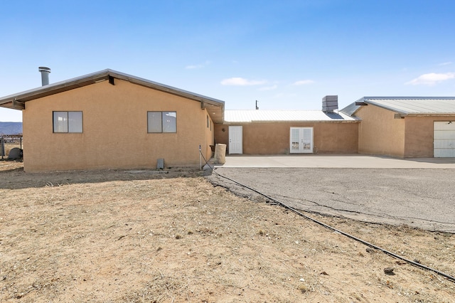 rear view of property with french doors, a patio, metal roof, and stucco siding