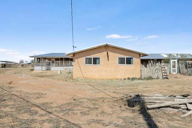 rear view of house with a sunroom and stucco siding