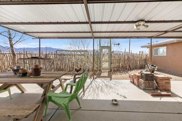 view of patio featuring outdoor dining area, fence, and a mountain view