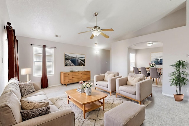 living room with visible vents, ceiling fan, light colored carpet, lofted ceiling, and arched walkways