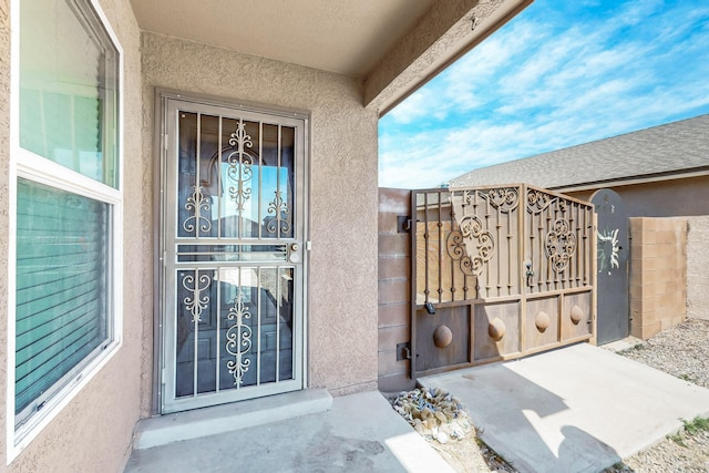 exterior space featuring stucco siding and a gate