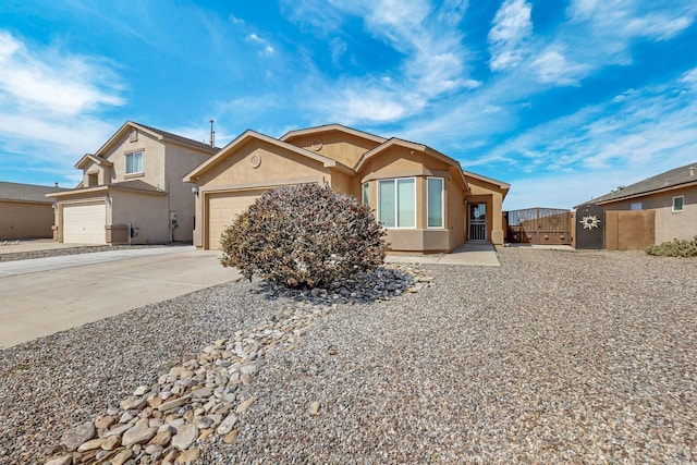 view of front of home featuring a gate, an attached garage, driveway, and stucco siding