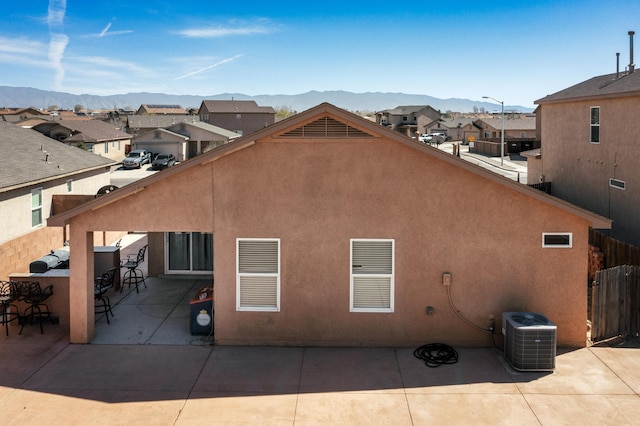 rear view of property featuring a patio, cooling unit, a mountain view, and stucco siding