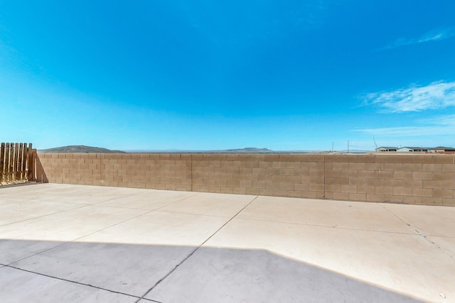 view of yard featuring a mountain view, a fenced backyard, and a patio