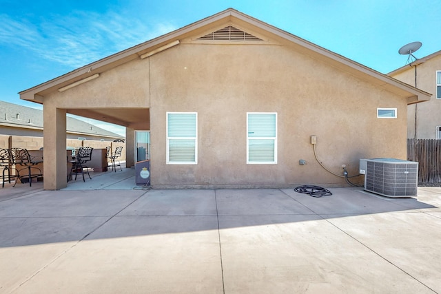 rear view of house featuring stucco siding, central AC unit, a patio, and fence