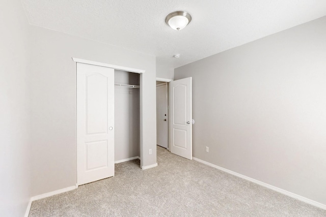 unfurnished bedroom featuring light colored carpet, baseboards, and a closet