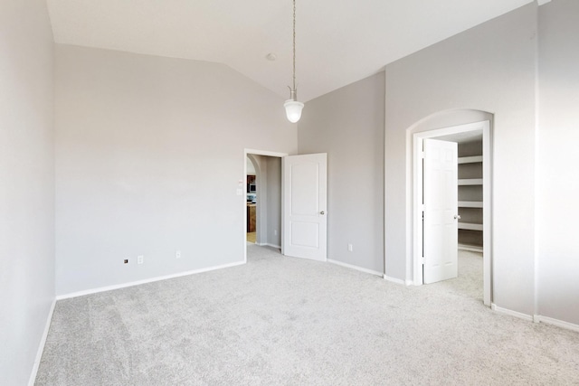 unfurnished bedroom featuring a spacious closet, arched walkways, baseboards, and carpet floors