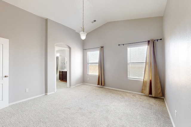 unfurnished room featuring baseboards, visible vents, lofted ceiling, arched walkways, and light carpet