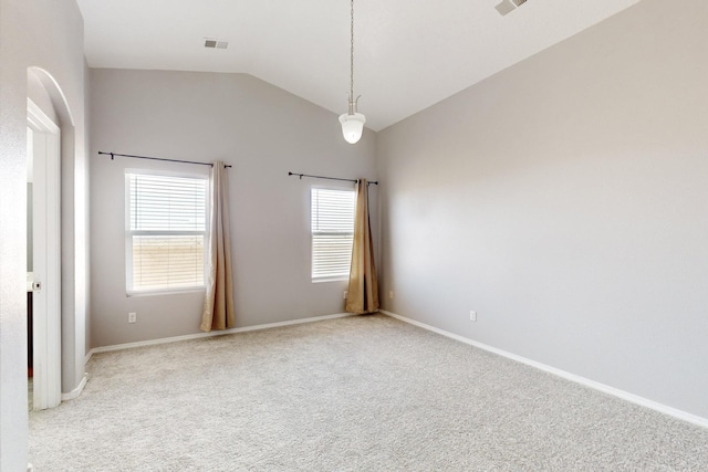 spare room with light colored carpet, lofted ceiling, baseboards, and visible vents