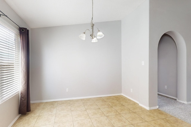 spare room with a notable chandelier, arched walkways, baseboards, and light tile patterned floors